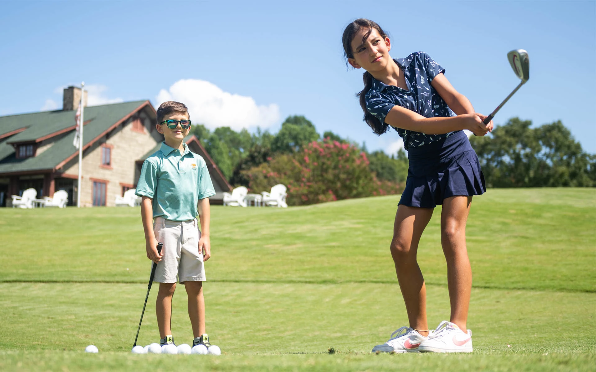 Invited's Crush It! Youth Golf Program in action: Two young children practicing to improve their short game, focusing on chipping.